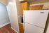Compact kitchen corner featuring a white fridge, wooden cabinetry, and vintage-style flooring for a cozy and functional apartment space.