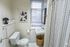 Chic and modern bathroom with stylish geometric art, bright window lighting, and elegant grid-patterned shower curtain.