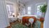 Charming bedroom with stylish decor, featuring a cozy bed, warm lighting, and lush indoor plant, perfect for relaxation.