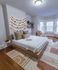 Charming bedroom with cozy decor, featuring a stylish wooden bed, soft textured rug, and elegant window seating with natural light.