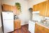 Charming kitchen with wooden cabinets, vintage gas stove, and modern coffee machine, accented by lush greenery.