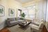 Charming living room with a modern gray sofa, elegant armchairs, and stylish decor, featuring natural light and cozy ambiance.