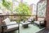 Chic urban balcony featuring modern patio furniture, lush greenery, and a patterned rug, perfect for relaxation.