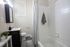 Elegant bathroom with modern fixtures, featuring a sleek vanity, cozy bathtub, and chic shower curtain alongside fresh decor elements.