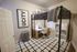 Cozy bedroom featuring a loft bed, modern workspace with a wooden desk, and a stylish rug beneath.