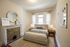 Bright and airy bedroom with elegant fireplace, plush bed, and cozy decor, bathed in natural light for a serene ambiance.