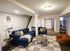 Cozy basement living area featuring a stylish blue sectional sofa, modern decor, and a relaxed reading nook with elegant lighting.