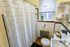 Charming bathroom with modern geometric shower curtain, natural light through window, and neatly arranged shelves.