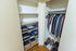 Spacious walk-in closet with organized shelving, hanging space, and footwear neatly arranged on a polished wooden floor.