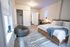 Inviting bedroom showcasing a modern design with a cozy bed, stylish decor, and a chic workspace under a neon lightning light.