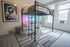 Chic urban bedroom with loft bed, vibrant cozy workspace, and large windows offering natural light.