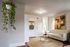 Elegant living room showcasing a chic cream sofa, modern round coffee table, and vibrant wall art. The hanging plant brings a touch of nature, enhancing the cozy and inviting atmosphere.