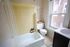 Bright bathroom with charming yellow tiles, a classic bathtub, large window, and modern decor accents.