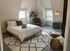 Inviting bedroom with cozy sloped ceilings, large windows, and elegant decor, featuring a plush bed and stylish seating area.