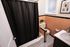 Chic bathroom with retro peach tiles, stylish black shower curtain, and modern fixtures, offering a blend of vintage charm and contemporary elegance.