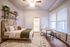 Bright and cozy bedroom featuring elegant wall shelves, a woven headboard, and inviting seating area.
