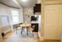 Cozy dining nook with a modern round table and stylish chairs, adjacent to a compact kitchen with sleek cabinets, perfect for intimate gatherings.