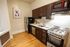Modern kitchen with stainless steel appliances, dark wood cabinets, and cozy artwork, offering a sleek and inviting cooking space.