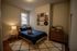 Cozy and stylish bedroom with a comfortable bed, geometric lamp, and charming vinyl wall display, ideal for urban living.