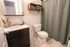Cozy modern bathroom featuring a sleek vanity, elegant tile flooring, and a soft green shower curtain for a relaxing retreat.