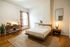 Cozy bedroom featuring a modern wooden bed, elegant decor, and a stylish work desk by a sunlit window.