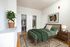 Inviting bedroom with stylish green bedding, elegant wooden furniture, and spacious closets. Features an artistic wall decor and a cozy atmosphere enhanced by a plush area rug and a touch of greenery.