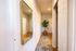 Elegant hallway with a large mirror, vibrant green plant, and stylish floral rug creating a welcoming atmosphere.