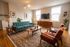 Chic and inviting living room with mid-century modern furniture, vibrant teal sofa, and large windows providing abundant natural light.