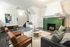 Elegant living room with plush seating, sleek hardwood floors, and a striking green tiled fireplace offering a cozy, modern ambiance.