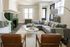 Charming living room with a cozy L-shaped gray sofa, elegant green-tiled fireplace, and stylish armchairs, perfect for relaxation and entertaining.