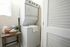Modern laundry nook featuring a stacked washer and dryer beside a rustic wooden table with laundry essentials.