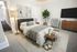 Cozy bedroom with modern decor featuring a sleek bed, ambient lighting, and a stylish rug. Elegant wooden furniture and a lush green plant enhance the room's tranquil ambiance.