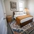 Inviting bedroom with a cozy bed, vibrant patterned rug, and stylish Philly wall art, illuminated by natural light.