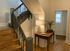 Charming hallway with rustic wooden staircase, elegant table, and soft-lit lamp, exuding warmth and style.