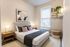 Cozy bedroom featuring a plush bed with modern decor, warm lighting, and stylish shelving, exuding comfort and elegance.
