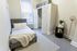 Cozy bedroom with a stylish single bed, plush pillows, and a warm blanket, featuring an elegant closet and modern decor for a comfortable living space.