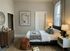 Inviting bedroom with minimalist decor, featuring a cozy bed adorned with decorative pillows, warm lighting, and elegant artwork.