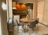 Charming dining area with a round wooden table and modern gray chairs, seamlessly blending into a cozy kitchen with warm wood cabinetry.