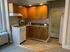 Cozy apartment kitchen with warm wooden cabinets, a compact white stove, and adjacent bath for convenience.