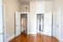 Bright, organized walk-in closet with elegant wardrobe showcasing fashion-forward clothing and footwear on rich hardwood floors.