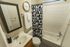 Chic bathroom with modern geometric shower curtain, wall-mounted clock, and elegant vanity mirror.