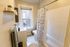 Bright and modern bathroom featuring a stylish shower curtain, sleek white tiles, and a large window for natural light.