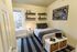 Cozy bedroom with modern decor, featuring a neatly made bed, stylish wall shelves, and a bright window. Perfect blend of comfort and style for a serene living space.