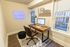 Chic home office with a neon 'Work Hard' sign, stylish wooden desk, and modern computer setup offering a productive workspace.