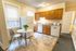 Inviting kitchen with warm wooden cabinets, modern appliances, and a cozy dining nook featuring a chic marble table with a decorative plant.