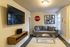 Contemporary living room with a sleek wall-mounted TV, cozy gray sofa, and modern decor including a stop sign and abstract art.