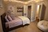 Cozy bedroom with elegant string lights, stylish wall art, and a comfy lavender bedding set. Features include a spacious closet, decorative shelves, and a charming bean bag chair.
