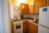 Cozy apartment kitchen with warm wooden cabinets, modern gas stove, and sleek countertops, ideal for culinary creativity.