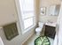 Charming bathroom with natural light, featuring elegant tiled flooring, a chic vanity, and a vibrant leaf-patterned rug.