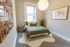 Cozy bedroom with stylish decor featuring a comfortable bed, soft green bedding, a large world map art piece, and a vibrant plant under a warm pendant light.
